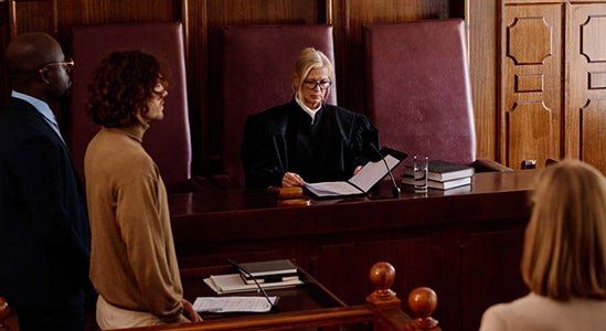 "A judge in a courtroom surrounded by people."